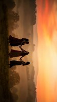 Three hikers silhouetted against dramatic sunset sky walking on mountain trail with backpacks during golden hour outdoor adventure expedition.