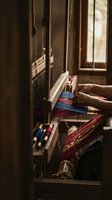 Traditional wooden loom with colorful threads in rustic workshop interior showcasing artisan textile weaving craft and handmade fabric production process.