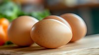 Fresh brown chicken eggs on wooden cutting board in modern kitchen setting for healthy cooking and baking recipes.