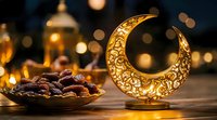 Glowing decorative crescent moon lantern with ornate pattern beside plate of dates, warm bokeh lights creating Ramadan ambiance and festive atmosphere.