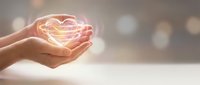 Hands holding glowing heart shape with warm light, symbolizing love, care, and compassion for charity, healthcare, and wellness concepts.