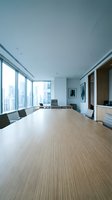 Modern conference room with wooden table, floor-to-ceiling windows overlooking city skyline, minimalist decor, and contemporary office furniture for corporate meetings.
