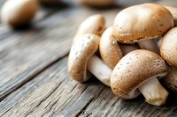 Fresh brown champignon mushrooms on rustic wooden background with selective focus and copy space. For food photography and menu design.