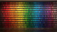 Massive library wall with thousands of colorful books arranged in rainbow spectrum from red to purple creating stunning gradient effect in modern interior space.