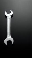 Chrome wrench tool isolated on dark gradient background for mechanical repair and maintenance work projects.