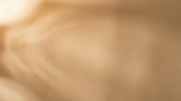 Soft golden beige abstract background with flowing light rays and gentle gradient transitions creating warm atmospheric depth for elegant design projects.