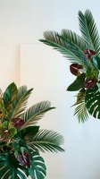 Tropical plants frame with palm leaves and anthurium flowers creating natural border on neutral background for summer design projects.