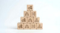 Wooden blocks stacked in pyramid formation with organizational hierarchy, teamwork, and management icons representing business structure and corporate leadership strategy.