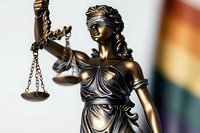 Bronze statue of Lady Justice holding scales against rainbow background, symbolizing equality and legal rights. Classical Themis sculpture represents law and order.