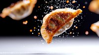 Crispy golden dumpling floating in air with sprinkled salt and spices against dark background, dramatic food photography with motion effect and bokeh lights.