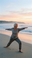 Senior woman practicing yoga in warrior pose on sandy beach at sunrise, promoting wellness, fitness and healthy lifestyle for mature adults.