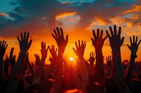 Silhouettes of raised hands against dramatic orange and teal sunset sky at outdoor music festival or concert, perfect for themes of unity, celebration, and community spirit.