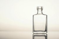 Empty transparent glass bottle with square shape and reflection on light beige background, suitable for premium spirits, perfume or cosmetic packaging design.