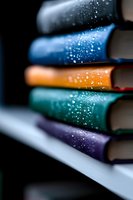Stack of colorful books with magical sparkle effect on dark background, selective focus on book spines creating dreamy atmospheric composition for reading concepts.
