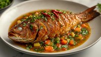 Whole roasted fish with herbs and vegetables in savory broth, gourmet seafood dish with carrots, peas and fresh garnish on white plate for culinary content.