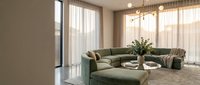 Spacious modern living room with sage green sectional sofa, ottoman, pendant lighting, and floor-to-ceiling windows with sheer curtains for interior design and home decor projects.