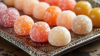 Colorful assorted fruit gummy candies covered in sugar crystals arranged on ornate metal tray. Sweet confectionery treats for dessert and snack concepts.