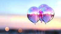 Transparent balloons reflecting sunset sky with pink and purple hues create dreamy romantic atmosphere against blurred bokeh background at dusk.