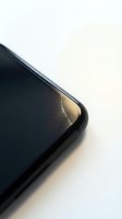 Cracked smartphone screen corner showing damaged glass with golden reflection on white background for repair and insurance concepts.
