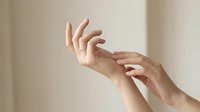 Close-up of two hands with light skin tone touching gently against neutral background, conveying care, connection, and tenderness for healthcare, wellness, and relationship concepts.