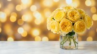 Yellow roses bouquet in glass vase on white table with golden bokeh lights background for romantic occasions and home decor.