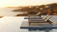 Luxury wooden lounge chairs on infinity pool deck overlooking ocean coastline at golden hour sunset for vacation resort relaxation and travel lifestyle.