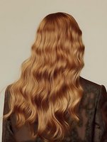 Back view of long wavy blonde hair on woman wearing brown jacket against neutral background, showcasing natural-looking waves and healthy hair texture.