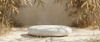 Minimalist white ceramic podium on sandy surface surrounded by dried grass and natural elements, suitable for product display and branding mockups.