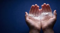 Open hands holding glowing white light energy with spiritual radiance against deep blue background for healing meditation and wellness concepts.
