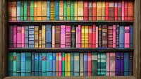 Colorful vintage books arranged on wooden library shelves creating rainbow pattern. Multicolored book spines in organized rows showcase diverse literature collection.