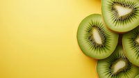 Fresh kiwi fruit slices on bright yellow background with copy space for healthy eating and nutrition concepts.