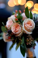 Peach roses with blue thistle and berries in romantic bouquet against soft bokeh lights, creating dreamy wedding atmosphere. Fresh floral arrangement.
