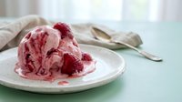 Scoop of raspberry ice cream with fresh berries on white plate, dessert food styling for culinary and recipe content.