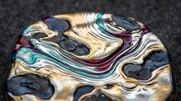 Colorful marbled abstract pattern with flowing liquid waves in gold, teal, purple and black creating dynamic swirled texture for modern design backgrounds.