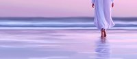 Young woman in flowing white dress walking barefoot on wet beach sand during sunset, creating reflection in purple and pink tones, cropped panoramic view.