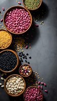 Assorted legumes and beans in wooden bowls on dark slate background. Healthy protein sources including kidney beans, lentils, chickpeas for cooking recipes.