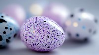 Speckled Easter eggs in pastel colors with black dots pattern on blurred background. Decorative purple and blue spotted holiday eggs create festive spring atmosphere.