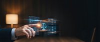 Businessman touching glowing digital legal interface with justice scales, representing modern law technology and online legal services in dark office.