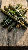 Fresh grilled asparagus spears with herbs and sea salt on rustic wooden cutting board for healthy cooking and gourmet meal preparation.