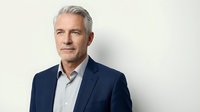 Mature man with gray hair wearing navy blazer and light blue shirt, isolated on white background for corporate and business use.