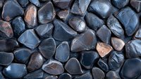 Polished wet river rocks in dark blue and copper tones create natural pattern background. Smooth stones texture for spa and wellness design.