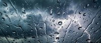 Raindrops on car windshield with stormy sky background creating atmospheric weather scene for automotive and climate concepts.