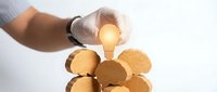 Business professional hand placing glowing light bulb among wooden circles representing innovative ideas and creative solutions for teamwork success.