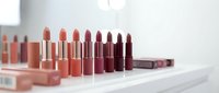 Collection of luxury lipsticks in nude to deep berry shades arranged on white surface for beauty and cosmetics branding.