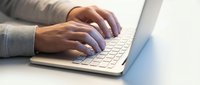 Professional hands typing on modern laptop keyboard in bright office environment for business and technology applications.