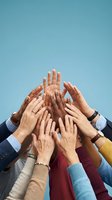 Diverse group of people raising hands together against blue sky, symbolizing unity, teamwork, and community collaboration.
