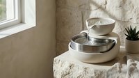 Modern ceramic tabletop water fountain with flowing water in minimalist beige interior design for relaxation and home decor wellness meditation space.