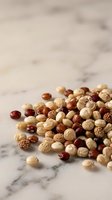 Mixed nuts including cashews, hazelnuts, and almonds scattered on marble surface for food styling, culinary content, and healthy snack promotion.