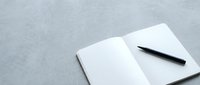 Open notebook with blank pages and black pen on gray textured surface, ready for writing, planning, or note-taking.