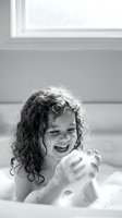 Happy young child with curly hair enjoying bubble bath time in bathroom, laughing and playing with soap bubbles in bathtub for hygiene and wellness concepts.